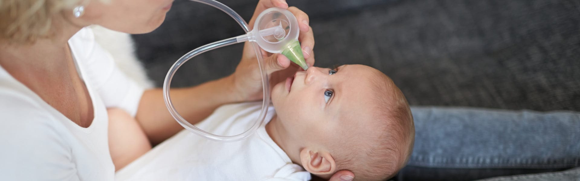 Una donna pulisce il naso del bebè con l'aiuto dell'aspiratore nasale manuale Nosiboo Eco