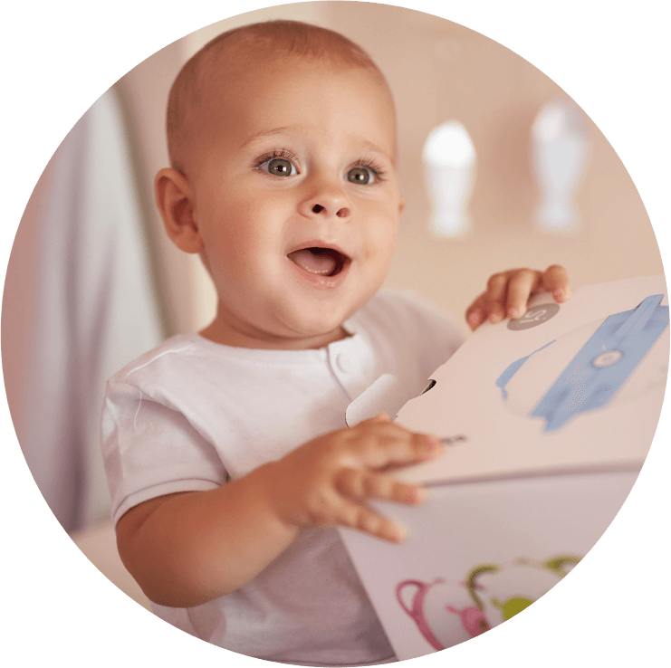 Un bambino affascinato tiene la scatola dell'aspiratore nasale elettrico Nosiboo Pro