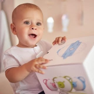 Un bambino affascinato tiene la scatola dell'aspiratore nasale elettrico Nosiboo Pro