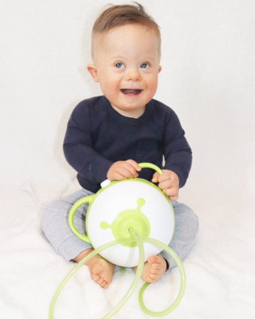 Un bambino sorridente tiene l'aspiratore nasale elettrico Nosiboo Pro in mano