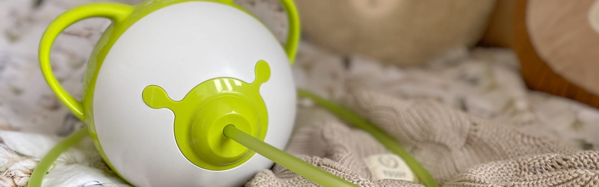 Aspiratore nasale elettrico Nosiboo Pro2 verde su un letto.