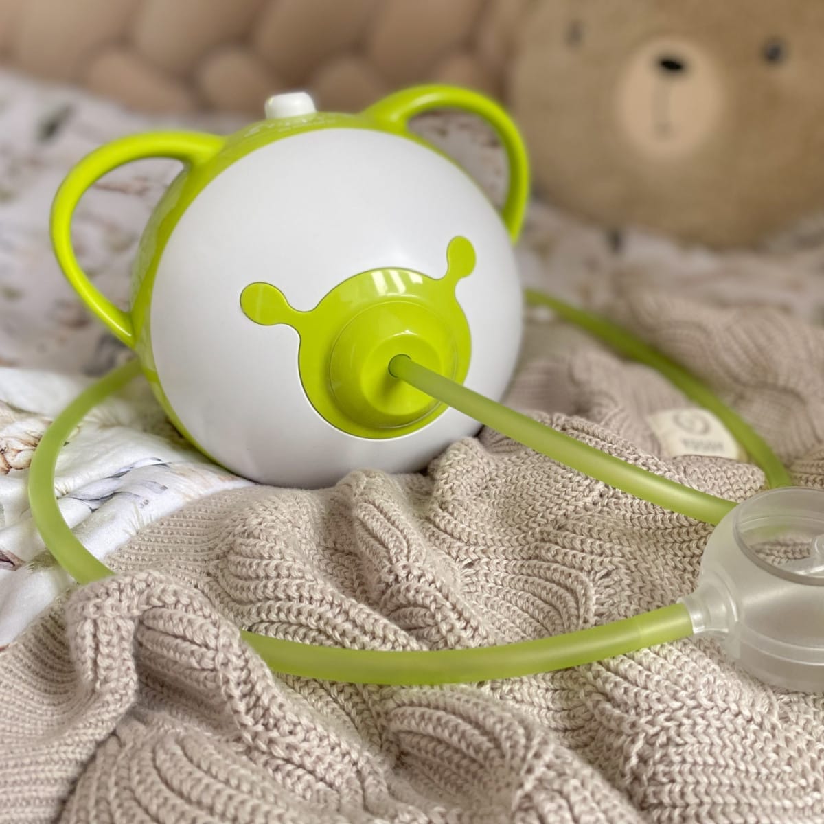 Aspiratore nasale elettrico Nosiboo Pro2 verde su un letto.