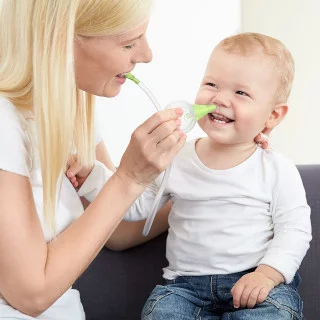 Un donna pulisce il naso di suo figlio che sorride, con l'aiuto dell'aspiratore nasale manuale Nosiboo Eco