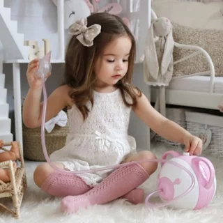 Une bambina elegante nella stanza sua con l'aspiratore nasale elettrico Nosiboo Pro in colore rosa