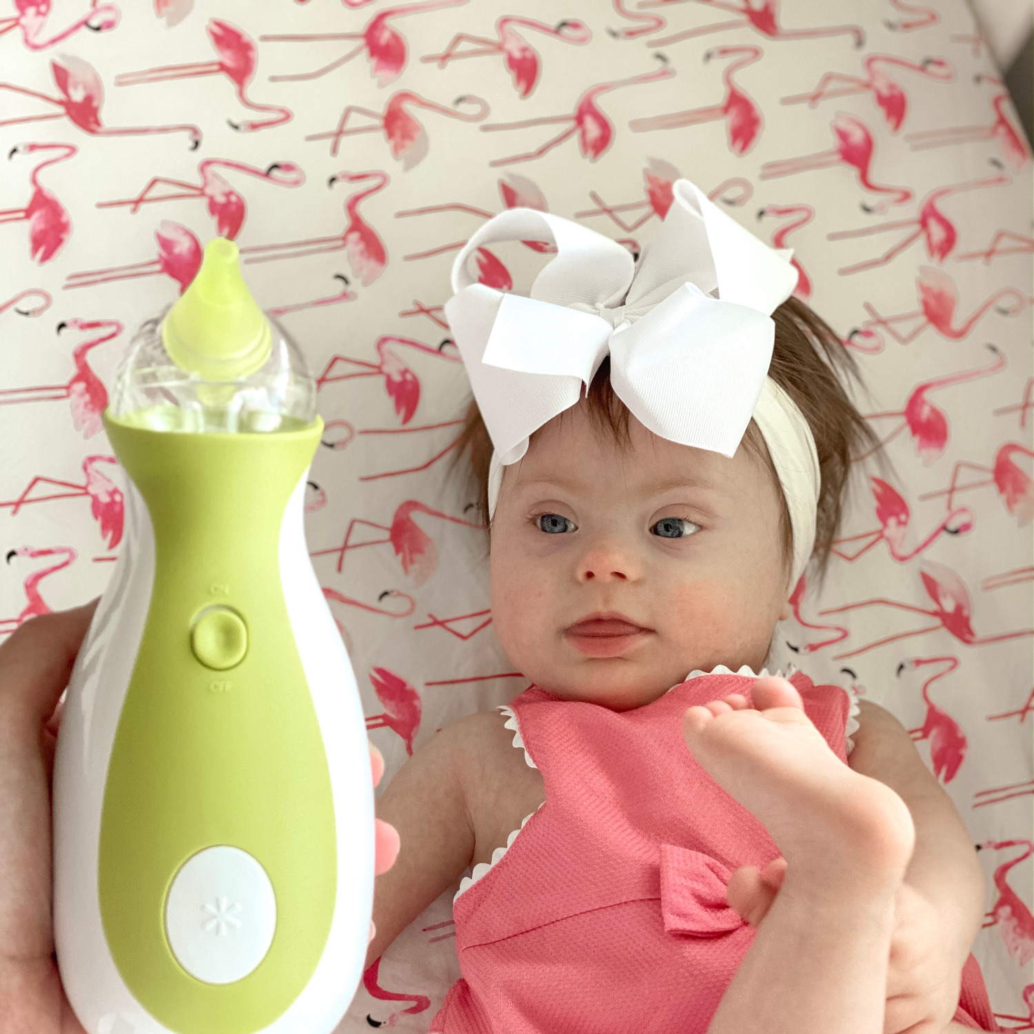 Little girl with Down syndrome looking at a Nosiboo Go portable electric nasal aspirator