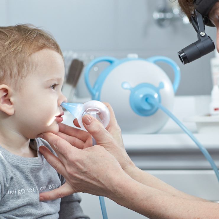 Un otorinolaringoiatra pulisce il naso di un bambino con l'aiuto di un aspiratore nasale elettrico Nosiboo Pro.