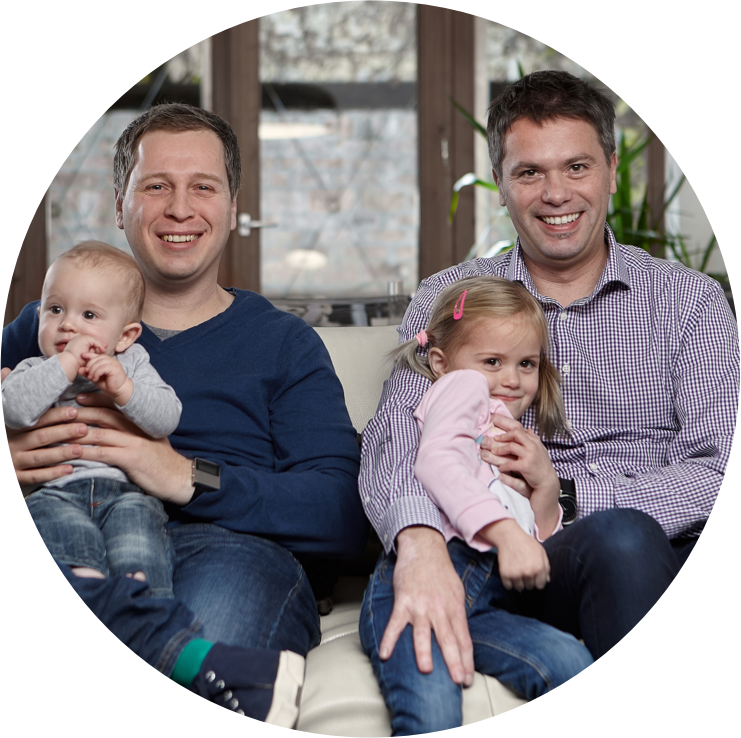 Two fathers, inventors of the Nosiboo products, sitting on a couch with their children and smiling